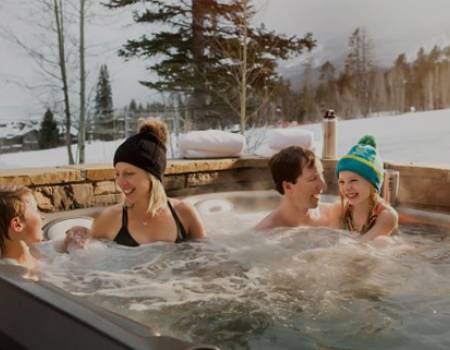 Family in hot tub outside of slopeside lodge