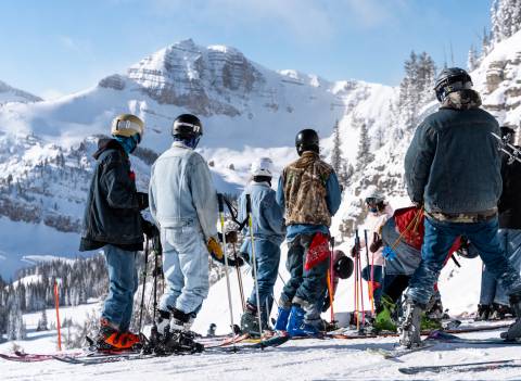 Skiers looking downhill in blue jeans