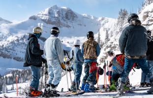 Skiers looking downhill in blue jeans